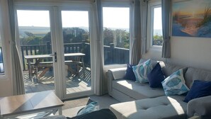 A bedroom with a sofa, a small table, and a view of the outdoors. - Valley View -panoramic views of Rame Peninsula (Torpoint)