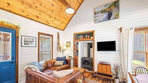 Un salon chaleureux avec une cheminée, des murs en bois et une porte bleue.