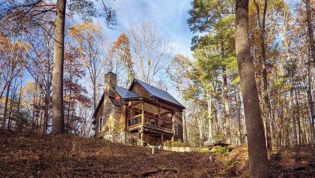 Une cabane en bois dotée d’un balcon, entourée d’une forêt.