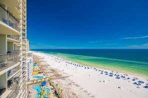 A beachfront hotel with a pool, beach umbrellas, and a clear view of the ocean. - Phoenix West 1203 3 Bedroom Condo (Orange Beach)
