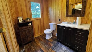 Ein Badezimmer mit Holzwandverkleidung, Toilette, Waschbecken und Waschtisch.