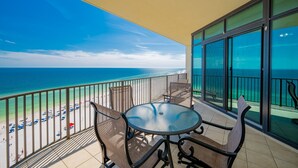 A balcony with a glass railing overlooking a beach.