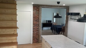 Una cocina moderna con encimera de mármol, suelo de madera y una pared decorativa de ladrillo.