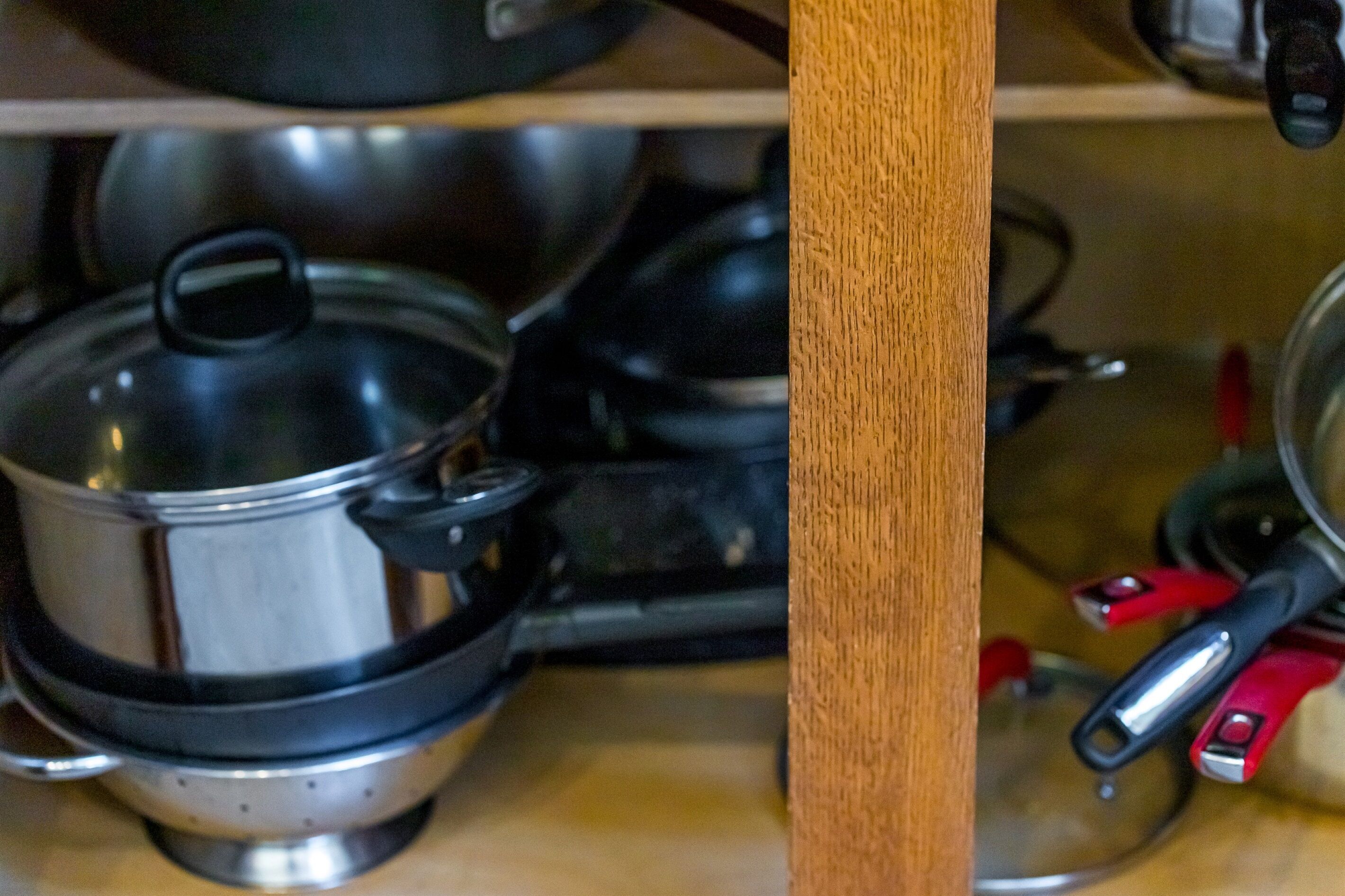 A kitchen with stainless steel cookware, including pots and pans, on a wooden countertop.