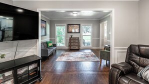 A living room with hardwood floors, a flat-screen TV, a leather sofa, a coffee table, and a fireplace. - Spacious Master's Rental w/Pool in the Heart of Evans (Evans)