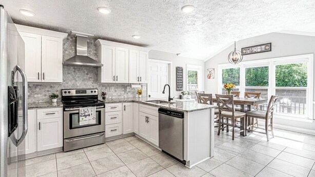 A modern kitchen with white cabinets, stainless steel appliances, and a large island with seating. - Spacious Master's Rental w/Pool in the Heart of Evans (Evans)