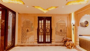 A grand entrance with intricate wooden carvings, a large double door, and a chandelier. - Hotel Ratan Mahal (Datia)