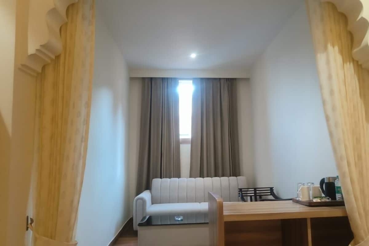 A room with a sofa, a small table with a tray of items, and a window with curtains.