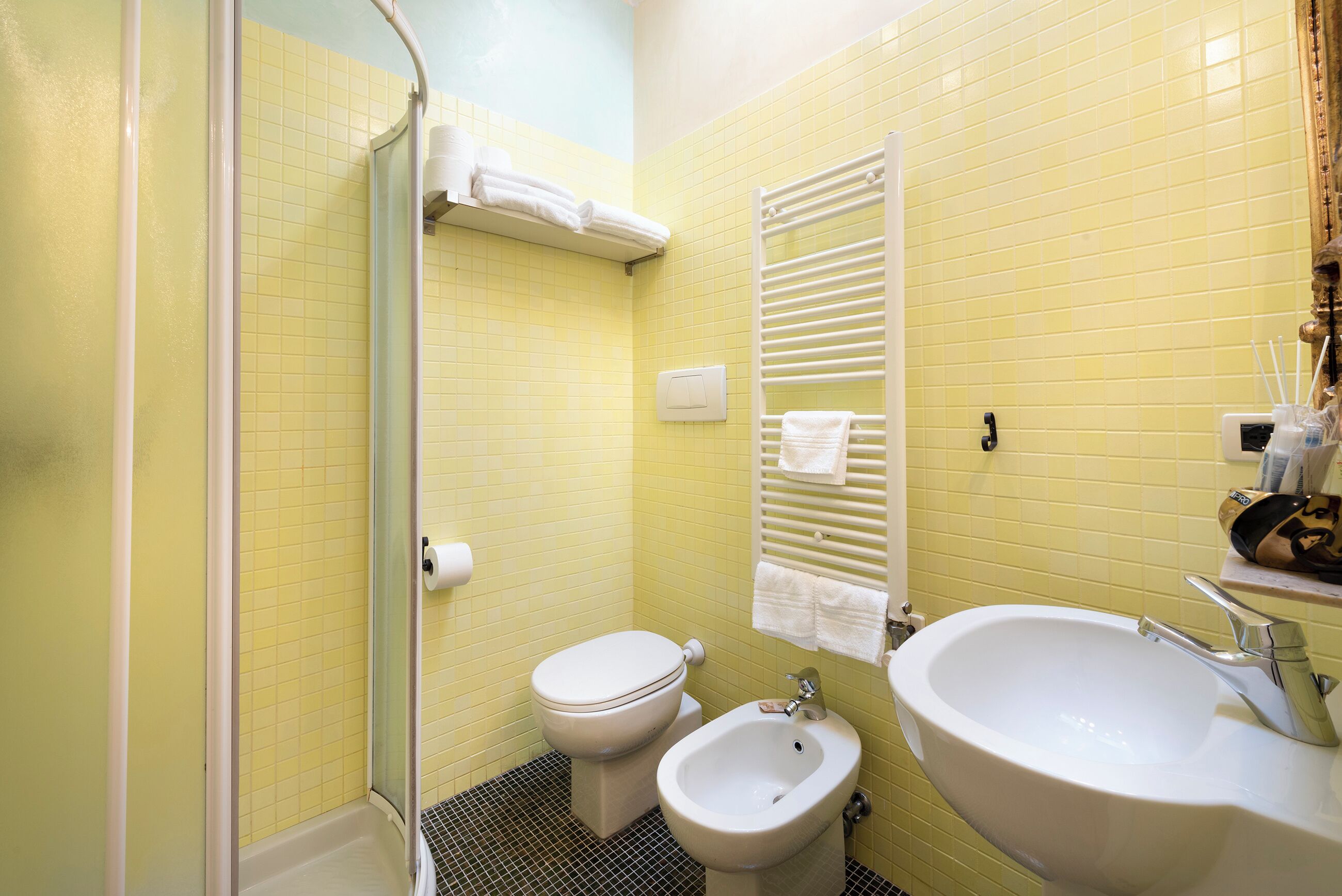 Ein Badezimmer mit gelben Fliesen, einer weißen Toilette, einem Bidet und einem Waschbecken.