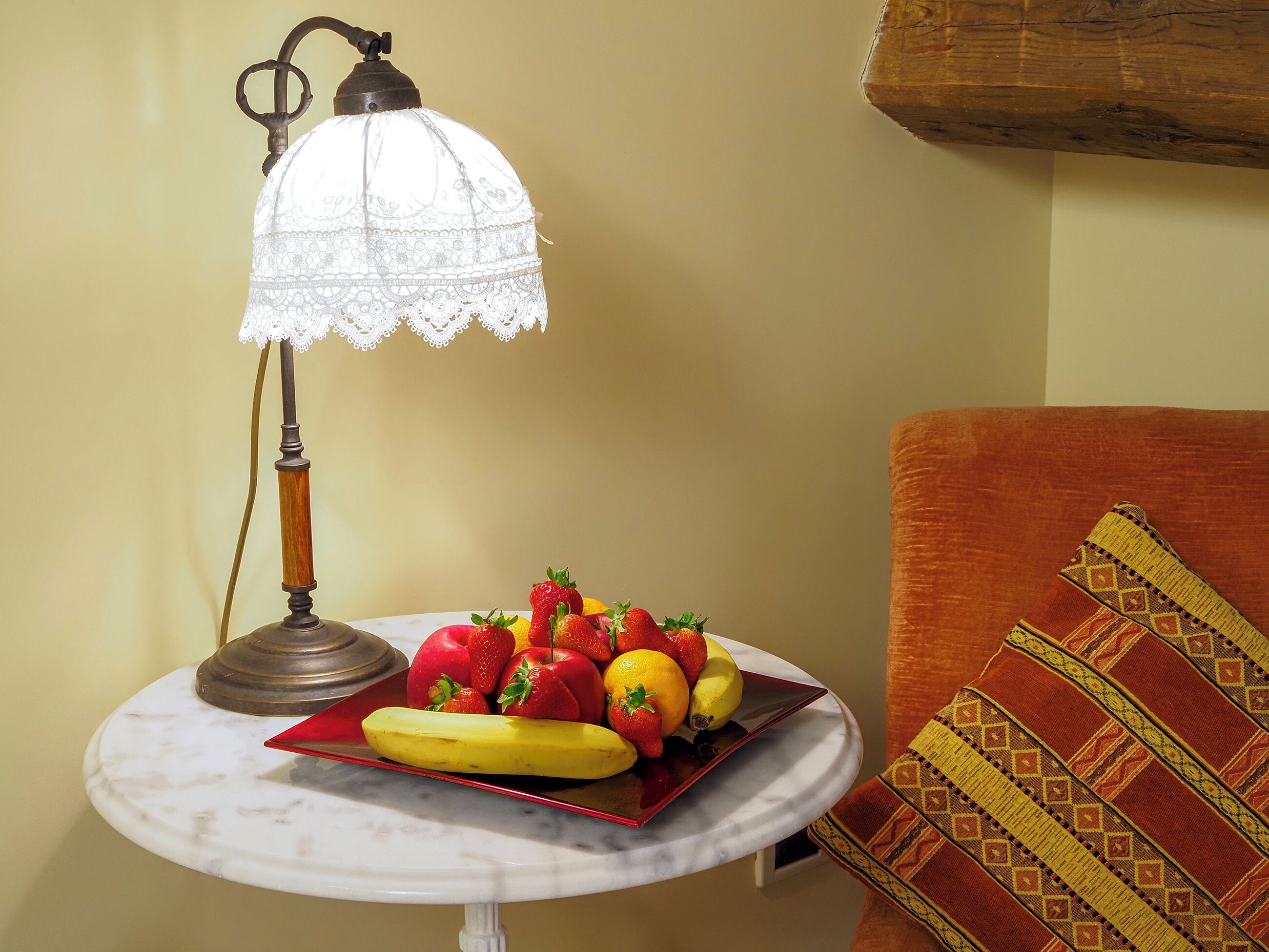 A table with a fruit platter and a table lamp.