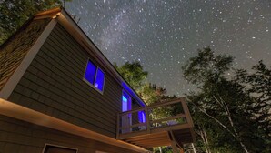 A house with a balcony under a starry sky. - Fantastic 3-bedroom with lake views, fishing, hiking, skiing and snowmobiling! (Alexandria)