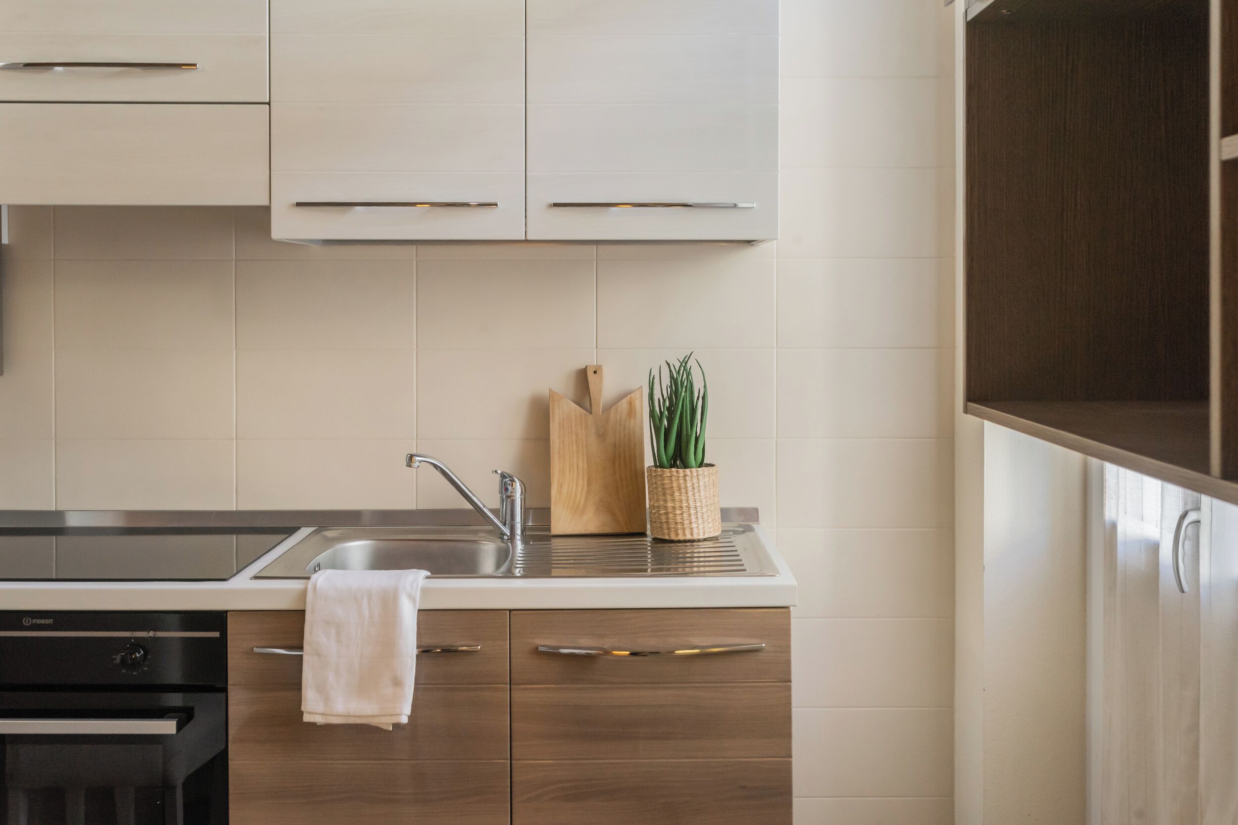 A modern kitchen with a stainless steel sink, wooden cabinets, and a built-in oven.