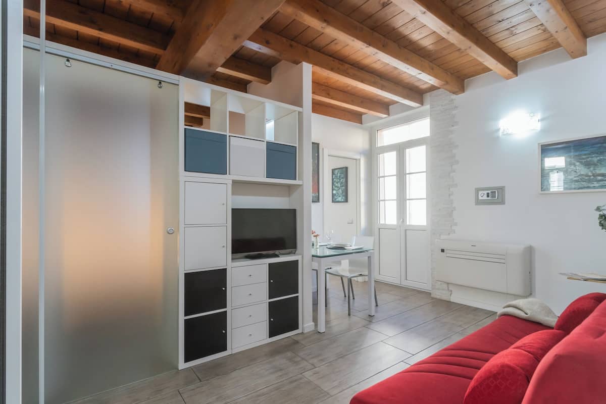 A compact living space with a kitchenette, a dining area, and a red sofa.