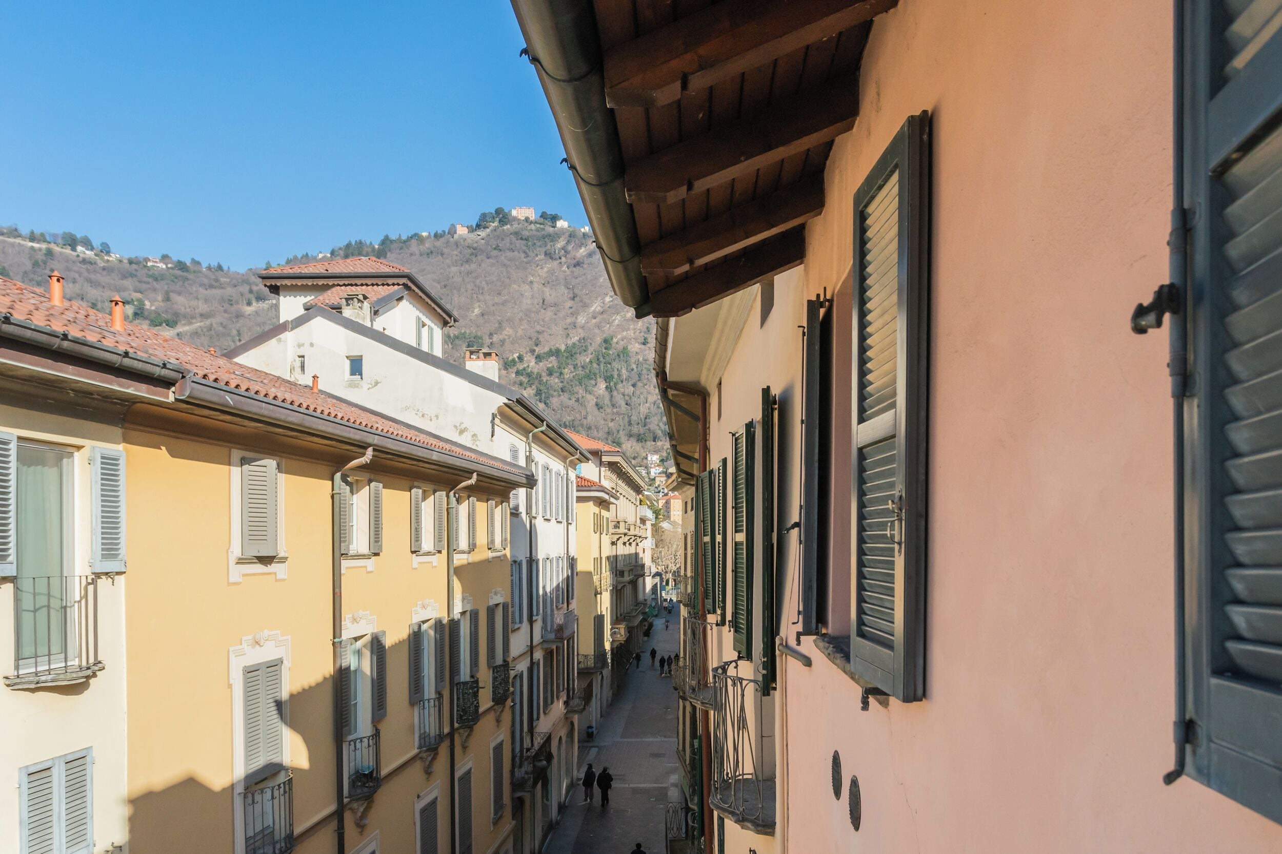 Una calle estrecha flanqueada por edificios, con balcones y contraventanas.