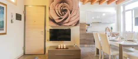 Una cocina moderna con comedor, vigas de techo de madera y una gran obra de arte con rosas en la pared.