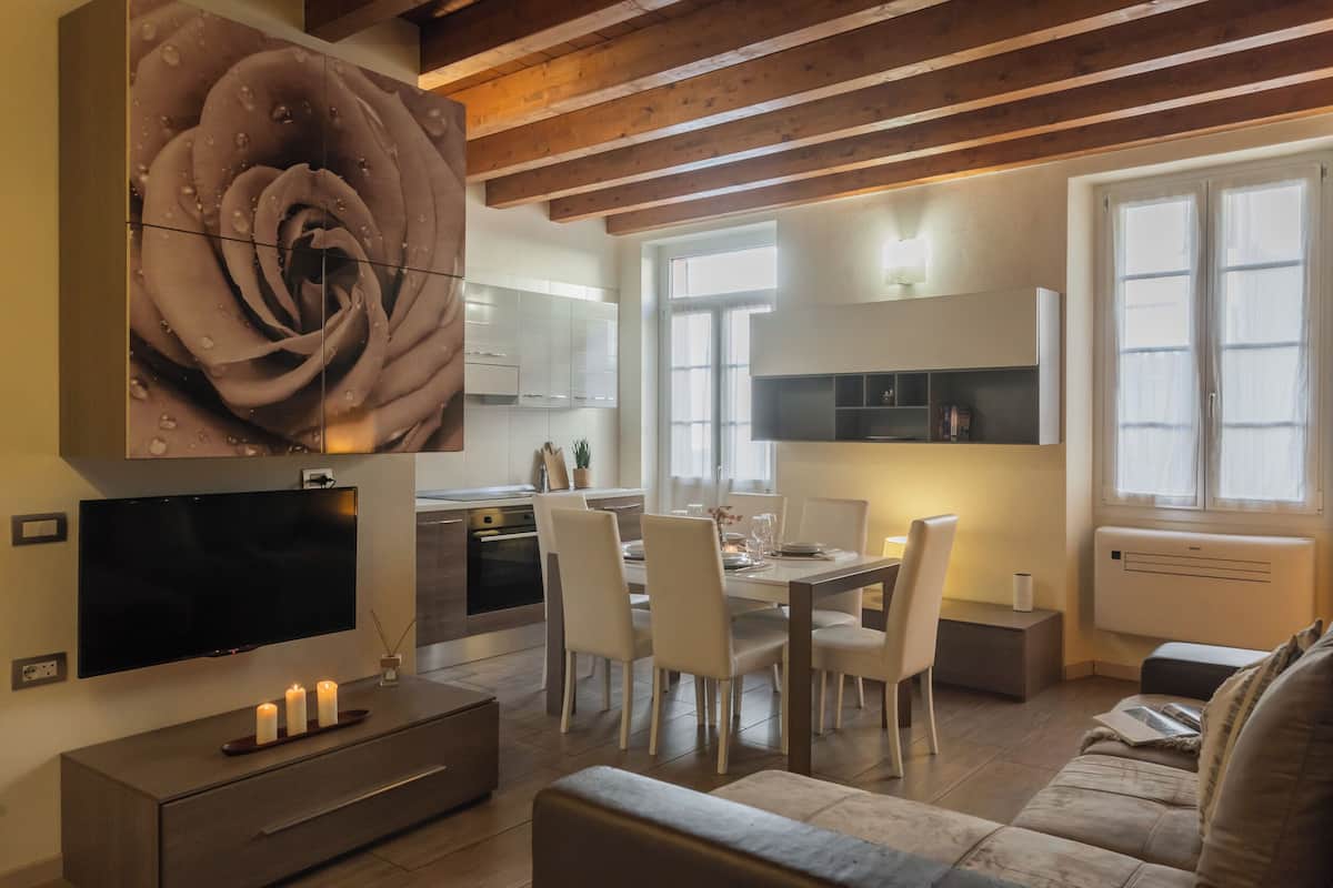 A modern kitchen with white cabinets, a dining area with a table set for four, and a large rose artwork on the wall.