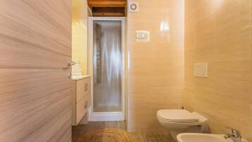 Ein kleines Badezimmer mit Holztür, Dusche, Toilette und Waschbecken.