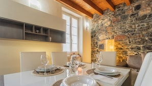 Un comedor con pared de piedra, mesa blanca y sillas.