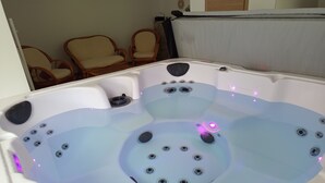 A hot tub with multiple jets, surrounded by wicker chairs. - 3-star rated house (sleeps 4) with private spa and garden (Bouvigny-Boyeffles)