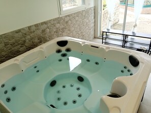 A hot tub with multiple jets, a stone wall, and a window with a view of the outdoors. - House for 4 people with a private spa & recreational facilities (Bouvigny-Boyeffles)