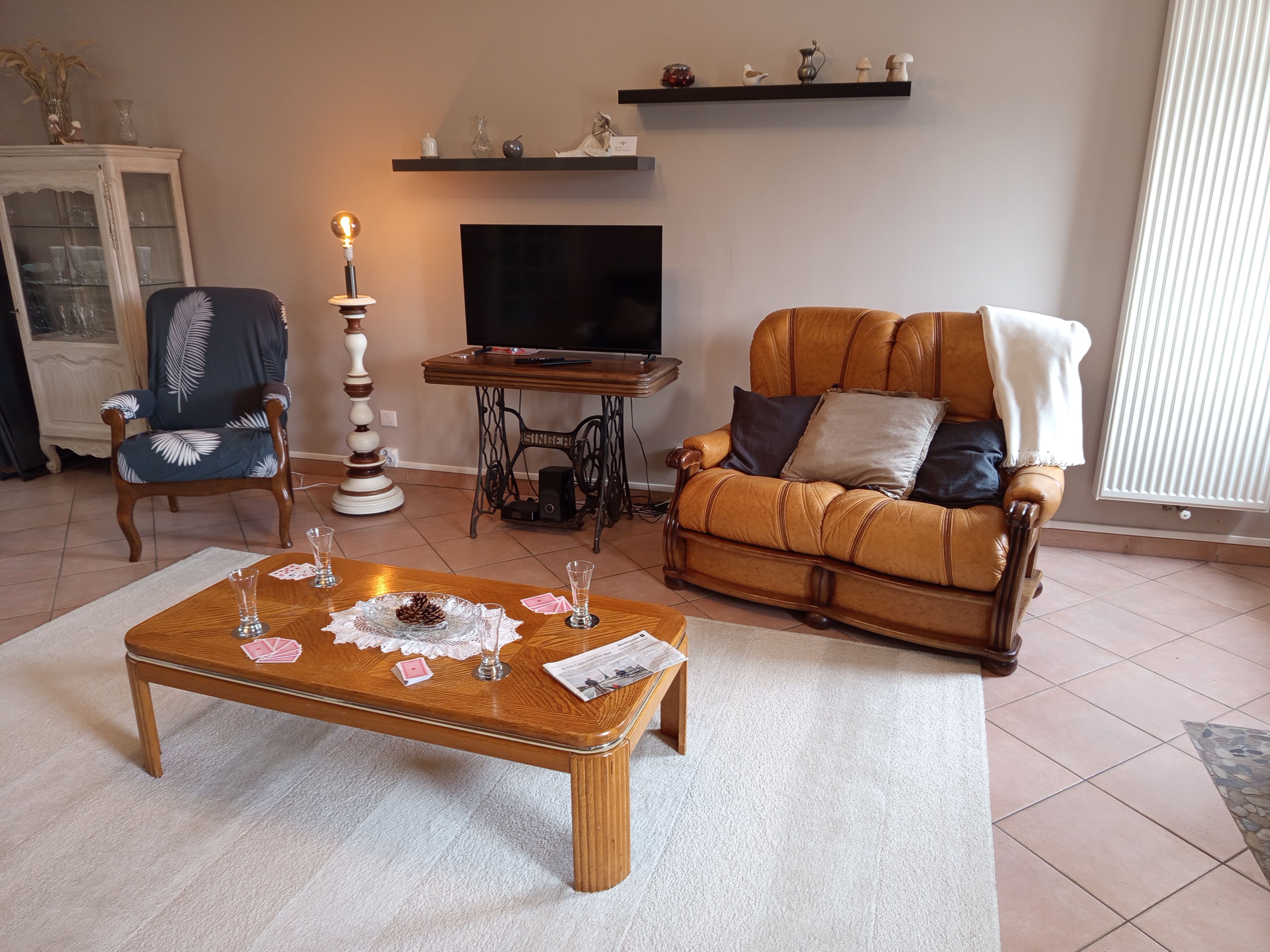 Un salon avec une table basse en bois, deux fauteuils, un téléviseur et un meuble.
