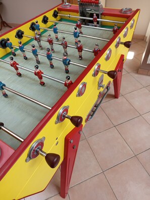 Ein Kicker mit roten und gelben Akzenten, ausgestattet mit Metallstangen und Spielfiguren.