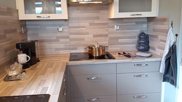 Une cuisine moderne dotée d’une cuisinière intégrée, d’une hotte en acier inoxydable et d’un pare-feu en carreaux.