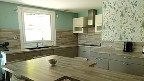 A modern kitchen with a central island, two chairs, a window, and a patterned backsplash. - 3-star rated house (sleeps 4) with private spa and garden (Bouvigny-Boyeffles)
