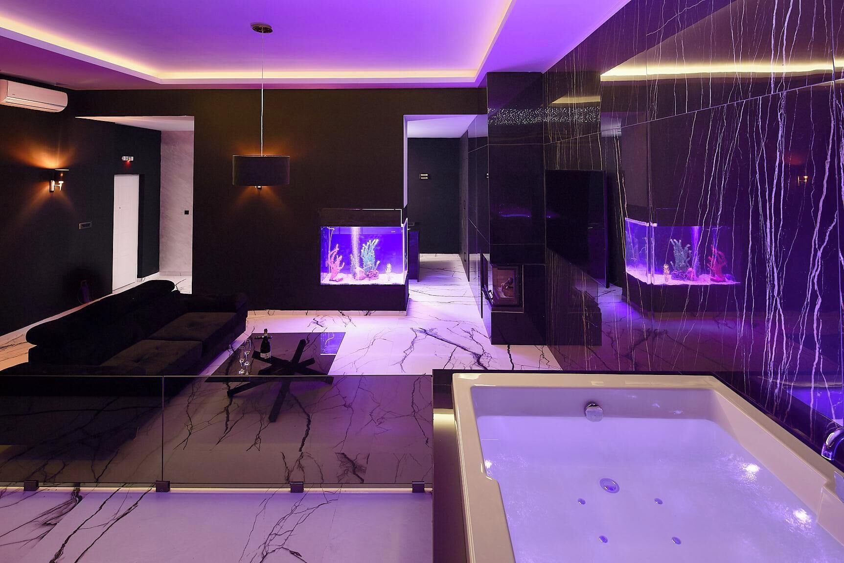 Un bagno moderno con una grande vasca da bagno, due acquari e un’area salotto con divano e tavolino.