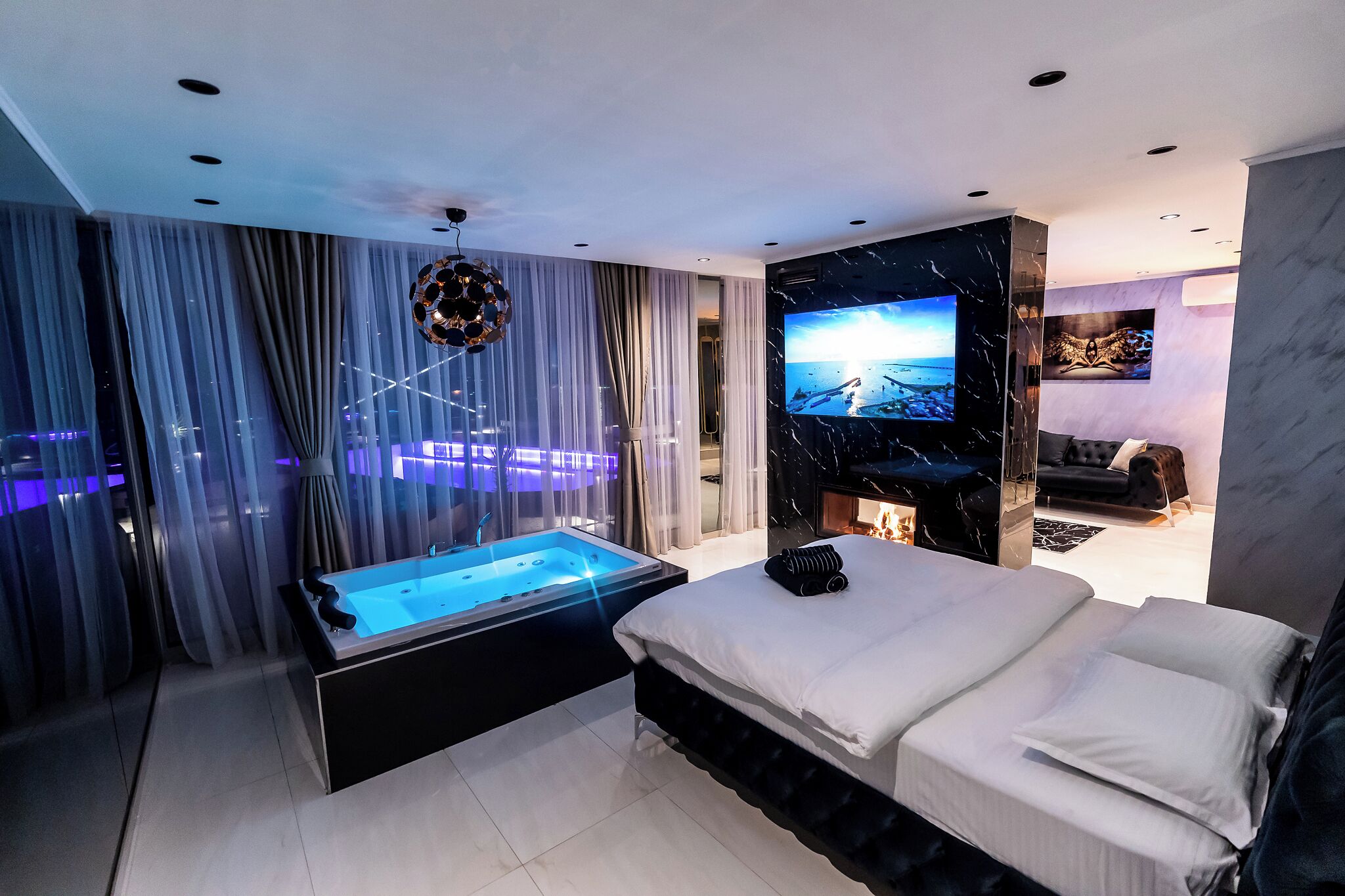 A modern bedroom with a large bed, a built-in TV, and a jacuzzi.