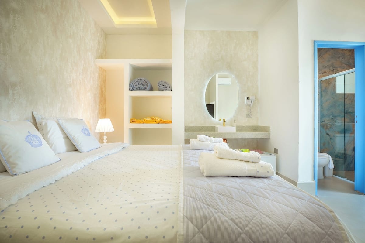 Une chambre d’hôtel avec un lit, une salle de bain avec un miroir et un espace douche.