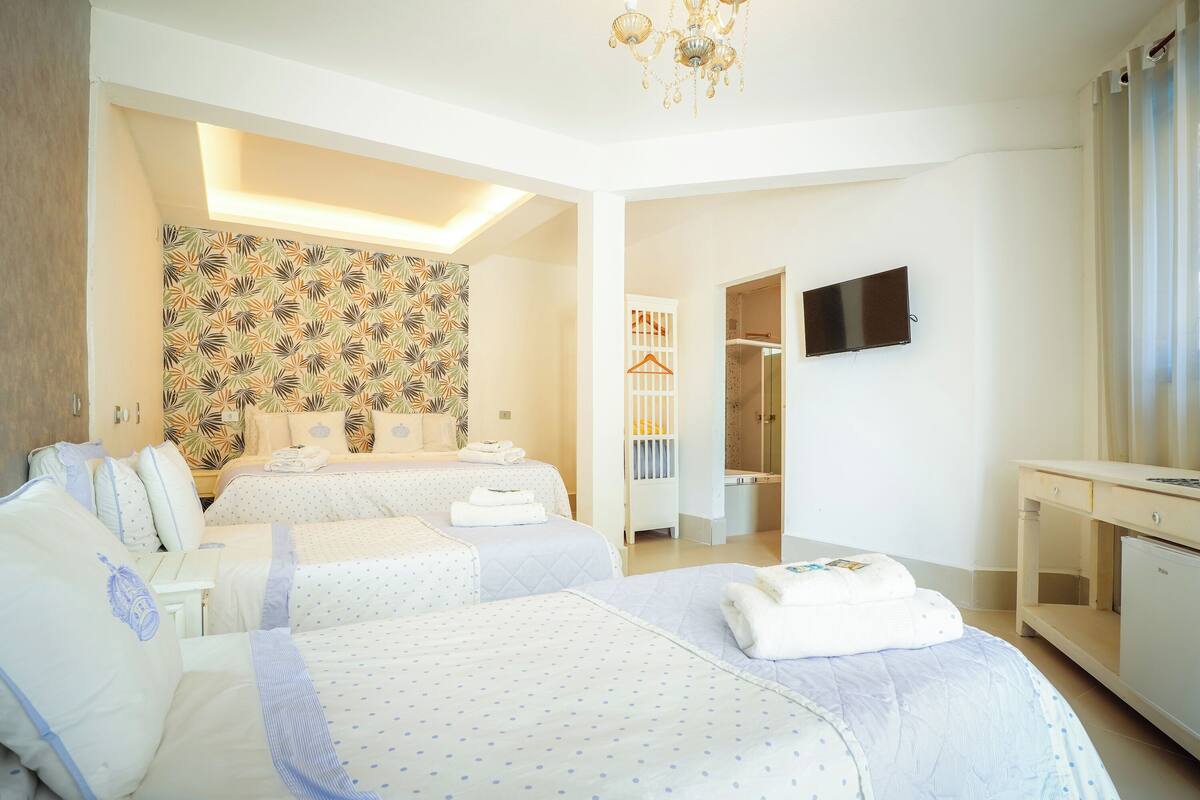 Une chambre d’hôtel avec deux lits, une télévision, un bureau et une armoire.