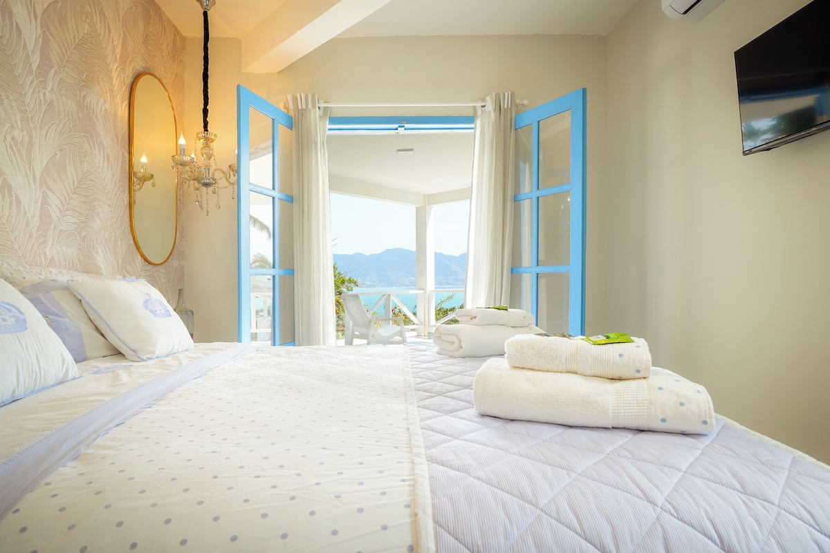 Une chambre avec un grand lit, une vue sur l’extérieur et un téléviseur fixé au mur.