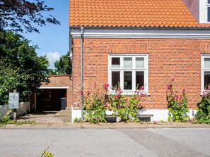 A brick house with a tiled roof, a garage door, and a mailbox. - 2 Person Holiday Home in Ringkobing (Ringkobing)