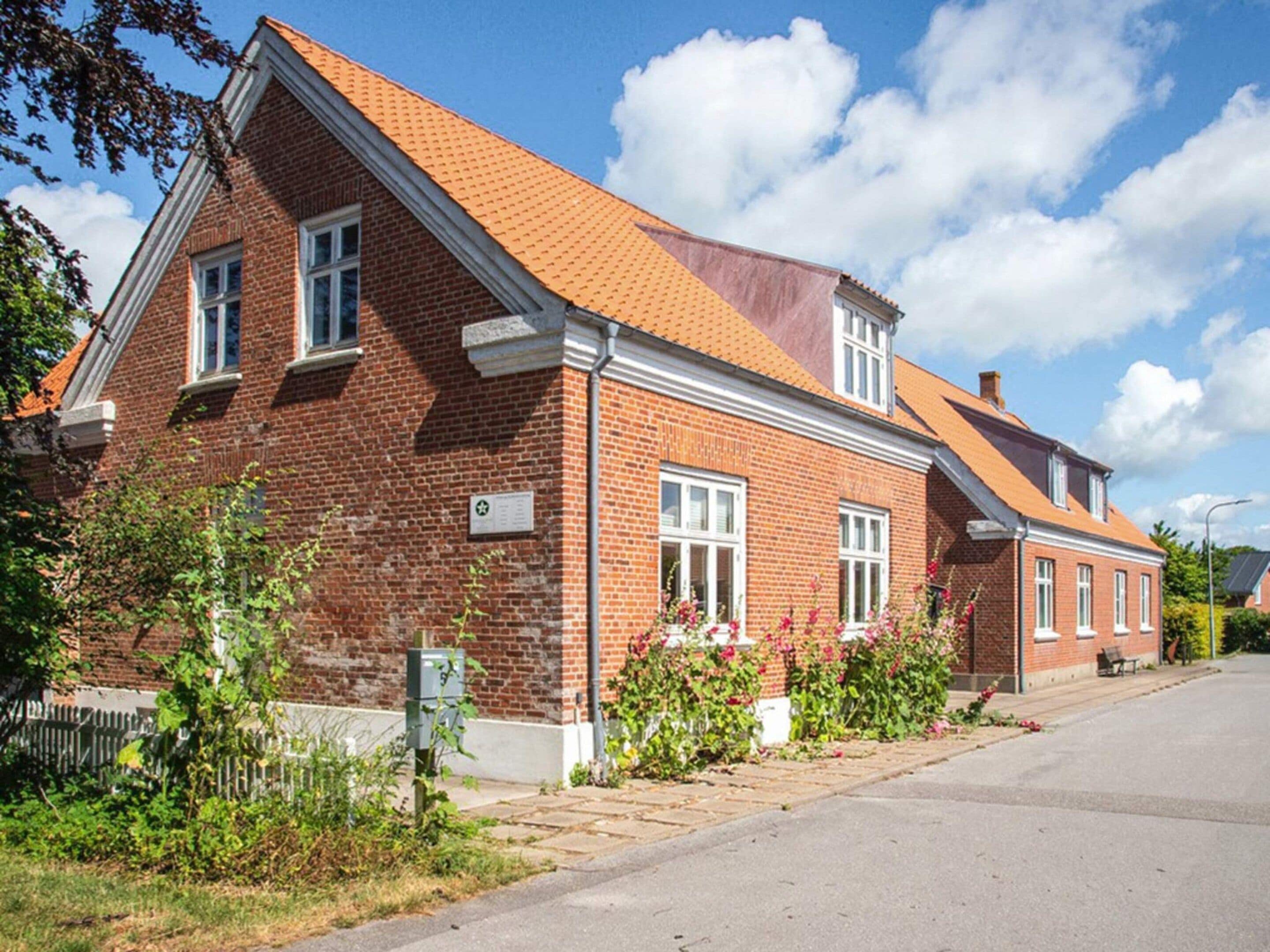 A two-story brick building with a sloped roof, a visible mailbox, and a paved driveway.