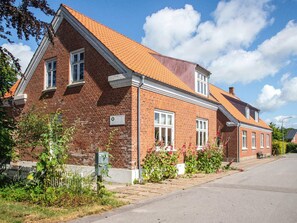 A two-story brick building with a sloped roof, a visible mailbox, and a paved driveway. - 2 Person Holiday Home in Ringkobing (Ringkobing)