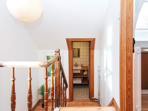 A staircase leading to a bathroom with a wooden door and a tiled wall.
