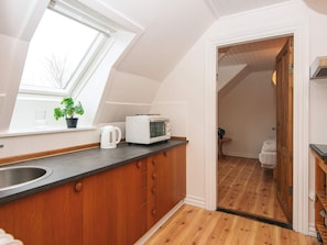 A kitchen with a window, a microwave, and wooden cabinets.