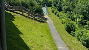 Vista de un área verde con un camino de madera que lleva a un edificio.