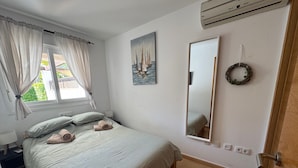A bedroom with a bed, a window with curtains, a painting, a mirror, a wall outlet, and a door. - Sunny Oasis Retreat in Condado del Alhama (Alhama de Murcia)