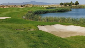 A golf course with a pond, sand bunkers, and distant mountains. - Sunny Oasis Retreat in Condado del Alhama (Alhama de Murcia)