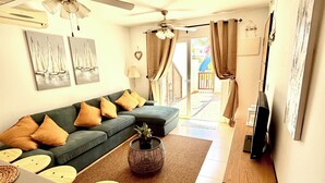 A living room with a sofa, coffee table, and a ceiling fan. There is a sliding glass door leading to an outdoor area. - Sunny Oasis Retreat in Condado del Alhama (Alhama de Murcia)