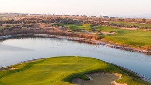 A golf course with a pond, sand bunkers, and a flag on the green. - Sunny Oasis Retreat in Condado del Alhama (Alhama de Murcia)