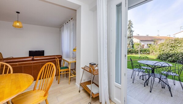 Relax in this open-plan living space with a sofa, dining table, and sliding door to a garden patio.