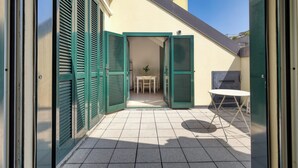 A patio area with a table and chairs, a small table, and a green door.