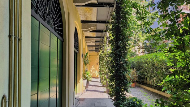 A narrow corridor with a tiled floor, a green door, and a metal gate.