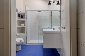 Een moderne badkamer met een douchecabine van glas, een wit toilet en een wastafel met spiegel.