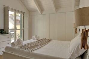 Een slaapkamer met een bed, nachtkastje, lamp en uitzicht.