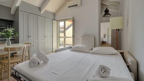 A hotel room with a bed, a desk, and a chair. There is a window with a view of the outside.