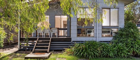 Uma casa moderna com varanda coberta, área de estar externa e um jardim bem cuidado.
